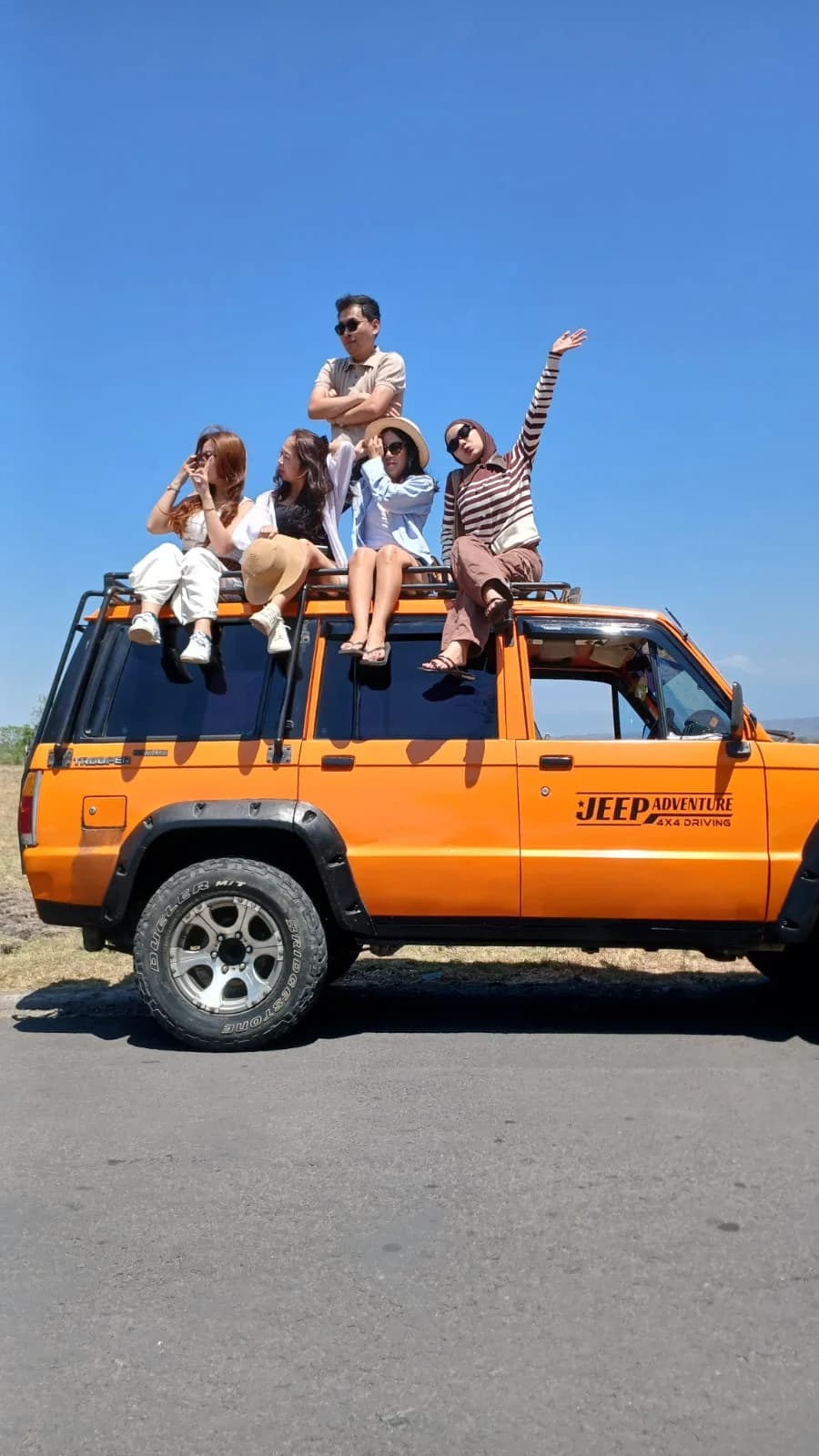 Keseruan wisatawan bersama rombongan berpose di atas Jeep oranye Baluran